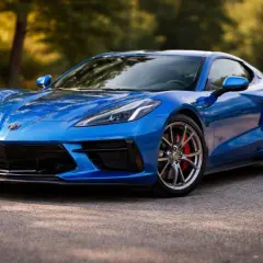 Niebieski Chevrolet Corvette C8, ikona wśród sportowych marek General Motors, prezentuje swoje dynamiczne linie na tle leśnej drogi.