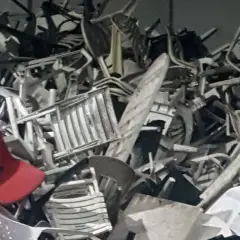 En stor hög med trasiga plaststolar, en röd stol sticker ut. Detta är en del av mjukplast sortering för återvinning.