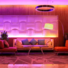 Nowoczesny hotel butikowy co to? Wnętrze z sofami, fotelami i designerską lampą w fioletowym świetle.