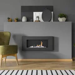 Nowoczesny biokominek w salonie, obok zielonego fotela, tworzy przytulną atmosferę.