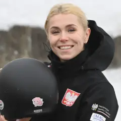 Uśmiechnięta Klaudia Adamek trzyma kask. Na jej kurtce widnieje godło Polski.
