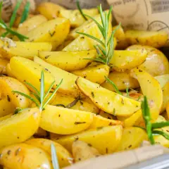 Goldgelbe rosmarinkartoffeln vom blech, knusprig und aromatisch, mit frischen Rosmarinzweigen garniert. Ein Genuss für Augen und Gaumen.