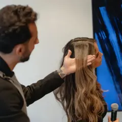 Hombre revisa el pelo elastico de una mujer, mostrando su textura y brillo.
