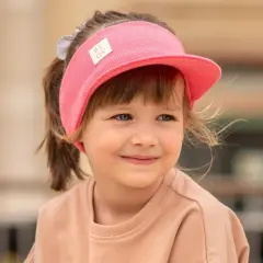 Uśmiechnięta dziewczynka w różowej opasce z daszkiem dla dzieci, gotowa na słoneczne przygody.