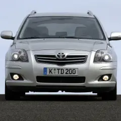 Srebrny Toyota Avensis z włączonymi światłami dziennymi i przeciwmgielnymi, gotowy do podróży.