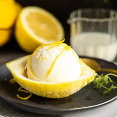 Erfrischendes Buttermilch Zitronen Eis, serviert in einer ausgehöhlten Zitrone, garniert mit Zitronenschale.