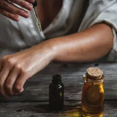 Una persona aplica aceite esencial en su brazo, mostrando cómo usar aceites esenciales para el cuidado de la piel.