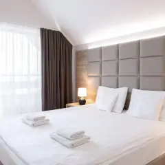 Przytulna sypialnia z dużym łóżkiem, miękkim zagłówkiem i zasłonami. "Room only" to oferta noclegu bez wyżywienia.