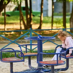 Smutna dziewczynka siedzi na karuzeli. Może to być jedna z zabaw dla 4 latka, ale dziś nie ma ochoty na zabawę.