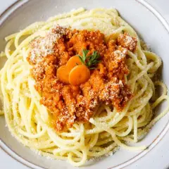 Spaghetti Bolognese, zubereitet im Thermomix, mit Karottenscheiben und Parmesan bestreut.