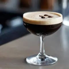 En perfekt espresso martini med krämig skum och tre kaffebönor som dekoration.