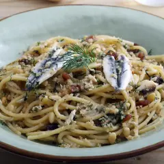 Un plat de pâtes aux sardines, garni de pignons de pin, de raisins secs et d'aneth frais.