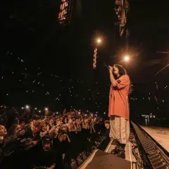 Billie Eilish w Polsce śpiewa dla tłumu fanów, którzy oświetlają scenę telefonami.