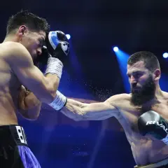 A light heavyweight boxer attempts to block a powerful punch from a heavyweight opponent in a dramatic boxing match.