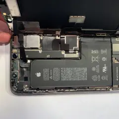 Rozłożony iPhone, gotowy do usuwania wody. Widać baterię, aparat i inne komponenty.