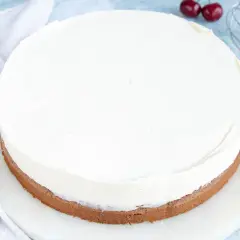 Ein runder Kuchen mit einer dicken Schicht luftiger **Mascarponecreme**. Kirschen und ein Schneebesen deuten auf die Zubereitung hin.