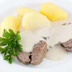 Zartes Krenfleisch mit Salzkartoffeln und cremiger Soße, ein Klassiker aus Bayreuth, garniert mit Petersilie.