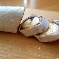 Roladki z tortilli z bananem i czekoladą na desce.