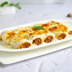 Canelones de carne gratinados, cubiertos con bechamel y queso derretido, listos para disfrutar.