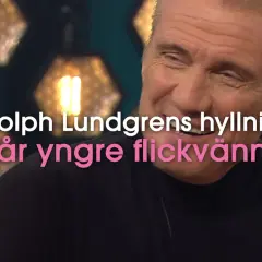 Dolph Lundgren, känd för sin kampsport, ler. Texten lyder: "Hör Dolph Lundgrens hyllning till 37 år yngre flickvännen".
