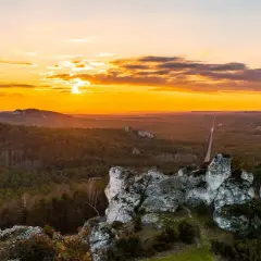 Zachód słońca nad Jurą Krakowsko-Częstochowską. Skaliste formacje i lasy tworzą malownicze krajobrazy, idealne na odkrywanie atrakcji.