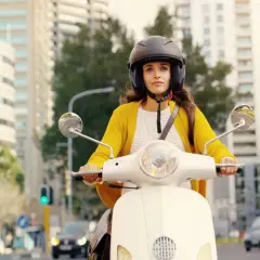Kobieta w żółtym swetrze na skuterze 50cc. Czy na motor 50 trzeba mieć prawo jazdy? Zapytaj ją, gdy przejedzie obok!
