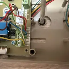 Wnętrze domofonu, gdzie żarówki słabo świecą, ukazuje plątaninę przewodów i złącz.