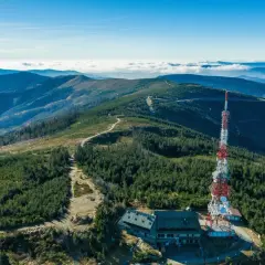 Widok na szczyrk jakie góry, z wieżą telekomunikacyjną i schroniskiem na tle pasm górskich i morza chmur.