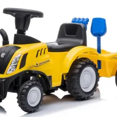 Żółty traktor New Holland z przyczepą, zabawka dla małego rolnika. Ma czarne siedzenie, kierownicę i niebieską łopatkę.