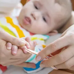 Delikatne pierwsze obcinanie paznokci u noworodka. Mama ostrożnie skraca malutkie paznokietki, by chronić go przed zadrapaniem.