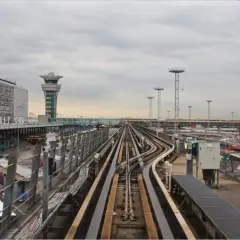 Vue depuis le train automatique Orlyval, avec la tour de contrôle et les voies ferrées. On imagine un voyage vers la Tour Eiffel.