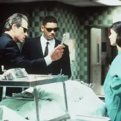Faceci w czerni obsada: Tommy Lee Jones i Will Smith badają tajemniczy obiekt, podczas gdy Lara Flynn Boyle obserwuje.