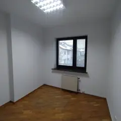 Puste, białe pomieszczenie z drewnianą podłogą i oknem. Zastanawiasz się, ile trwa malowanie pokoju?