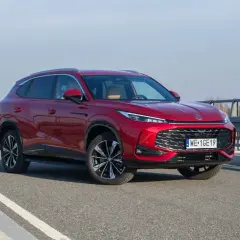 Czerwony MG HS Hybrid na drodze, z widocznym grillem i światłami LED. Elegancki SUV gotowy na podróż.