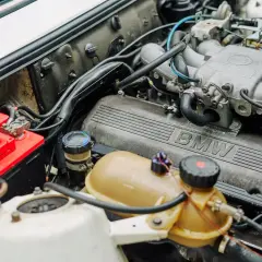 Silnik BMW z widocznym numerem OEM po VIN. Czerwony akumulator i zbiorniczek płynu chłodniczego.