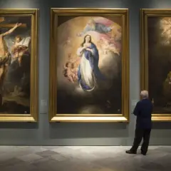 A man contemplates three religious paintings by Bartolomé Esteban Murillo in a gallery.