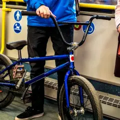 Chłopak z niebieskim rowerem BMX w autobusie, gotowy do podróży.