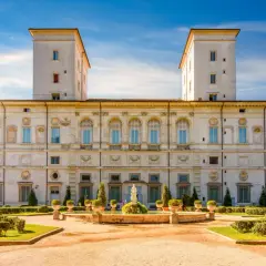 La Villa Borghese à Rome, avec ses tours jumelles et son jardin à la française, sous un ciel bleu éclatant.