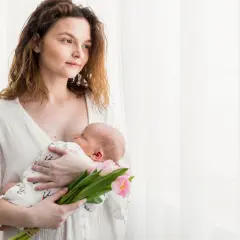 Mama tuli z dzieckiem na rękach, trzymając bukiet różowych tulipanów. To piękny obrazek z 4 trymestru.