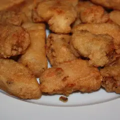 Un plato blanco lleno de trozos dorados y crujientes de japuta en adobo, listos para disfrutar.