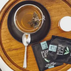 Aromatyczna, najlepsza czarna herbata Earl Grey z Sri Lanki, zaparzona w szklance, obok saszetki i łyżeczka.