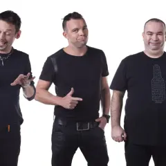 Trzech członków kabaretu Ani Mru Mru w czarnych strojach, każdy z innym wyrazem twarzy i gestem.