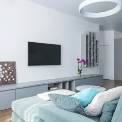 Nowoczesny salon z telewizorem na ścianie i szafką RTV, która pomaga jak ukryć kable na ścianie.