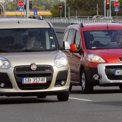 Złoty Fiat i czerwony Peugeot jadące po drodze.