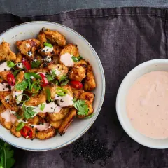 Krispiga kycklingbitar toppade med färska örter, chili och sesamfrön, serverade med en krämig bang bang sås.
