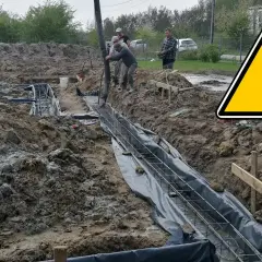 Budowa trwa: betonowanie ław fundamentowych. Pracownicy wylewają beton do wykopów z zbrojeniem.