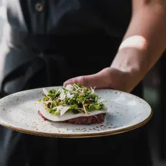 En kock presenterar en vacker tartar med örter och blommor, en delikatess från Torekov Hotell meny.