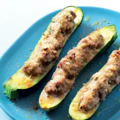 Tre zucchine ripiene velocissime, dorate e appetitose, servite su un piatto blu.