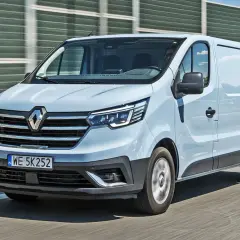Jasnoszary Renault Trafic 2.0 na drodze, z widocznym przodem i bokiem pojazdu.