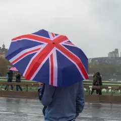 En person med ett paraply med brittiska flaggan på en regnig dag i London. En klassisk vy som visar vad man får inte missa i London.